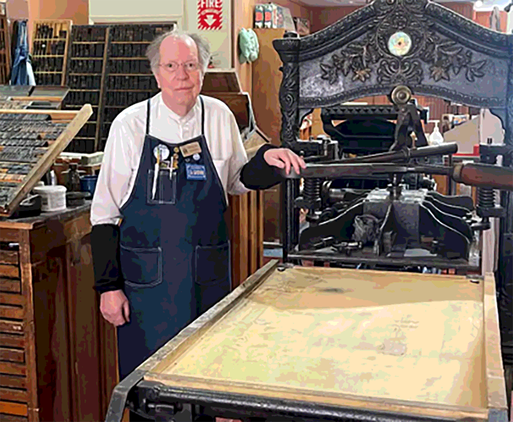 Howard Hatch standing next to historic printing press at Sacramento History Museum